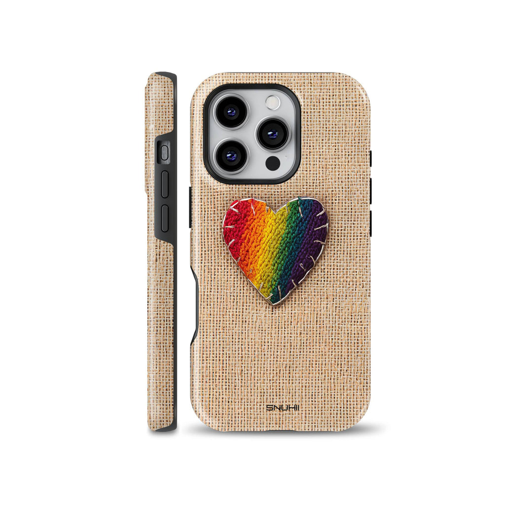 A cozy phone case featuring a rainbow embroidered heart patch with visible stitching on a beige burlap canvas background, designed for iPhone, Samsung, and Pixel.